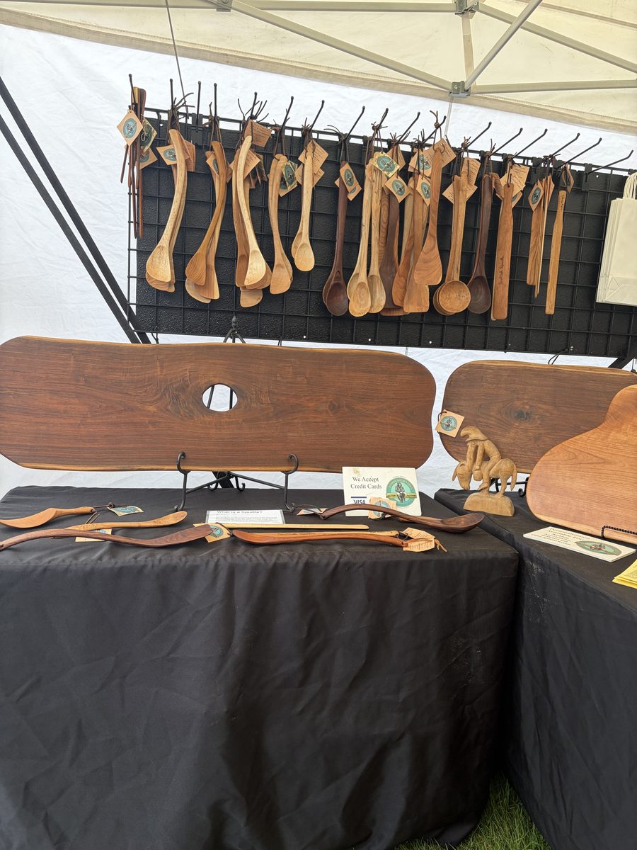 A rack of hand-carved wooden spoons and ladles hanging at the booth